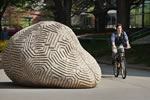 Bicycles are brought out of storage. A student rides past the 'Ridge and Furrow' sculpture along the Cleary Walkway.